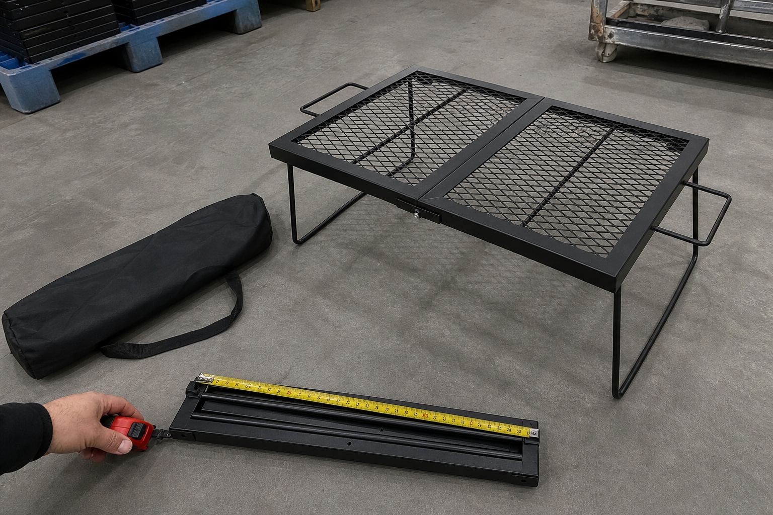 Clean foldable black camping grill and carry bag checked with a tape measure on a warehouse floor